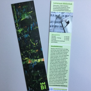 2 Lesezeichen: Vorderseite künstlerisch gestaltet in dunklen, fast schwarzen Farben mit einzelnen grün-bunten Strichen; Rückseite mit Text über die Musikbibliothek
