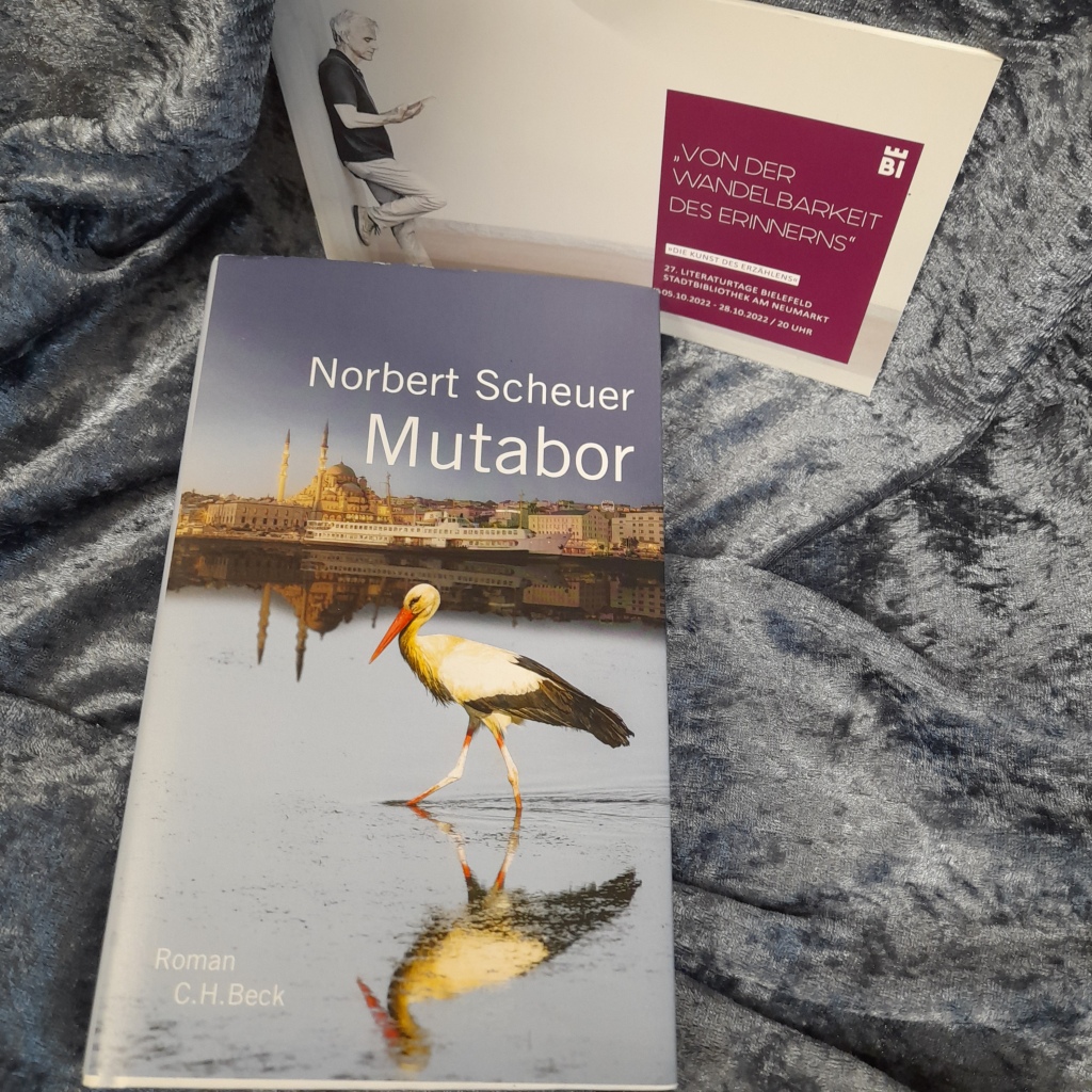 Roman "Mutabor" von Norbert Scheuer auf einem silbergrauen Tuch zusammen mit dem Programmheft der Literaturtage Bielefeld 2022