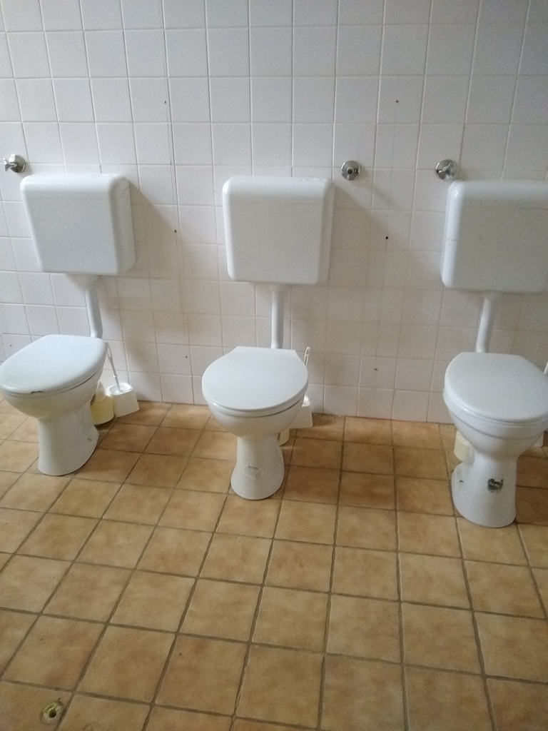 Drei Toilettensitze nebeneinander, die Kabinen fehlen