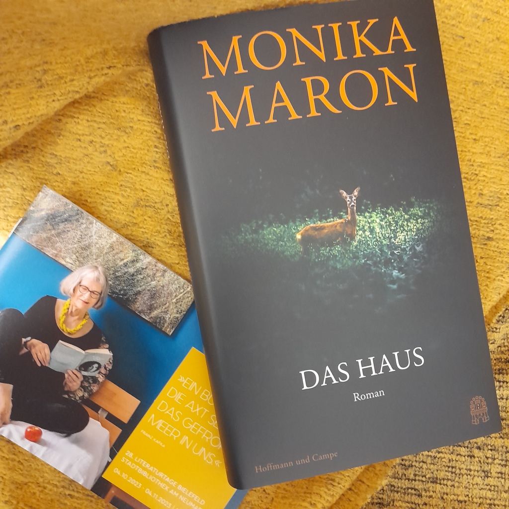 Roman "Das Haus" von Monika Maron und das Programmheft der Literaturtage 2023 liegen auf einem gelben Tuch