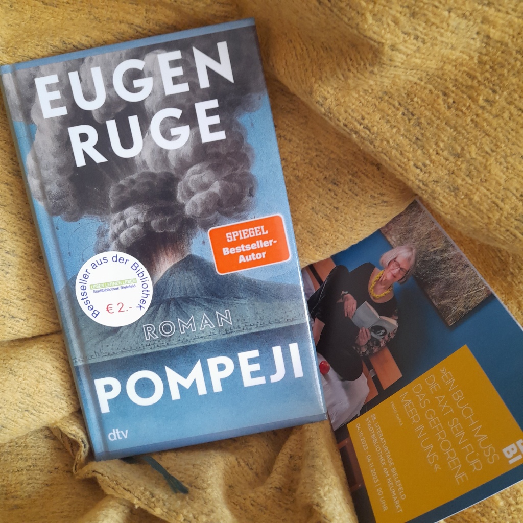 Auf einem gelben Tuch liegen der Roman-Bestseller "Pompeji" von Eugen Ruge, dtv-Verlag, und das Programmheft der Literaturtage Bielefeld 2023