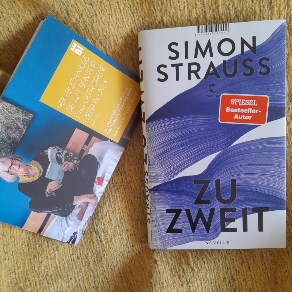 Auf einem gelben Tuch liegen das Programmheft der Literaturtage und die Novelle "Zu zweit" von Simon Strauss; Tropen-Verlag