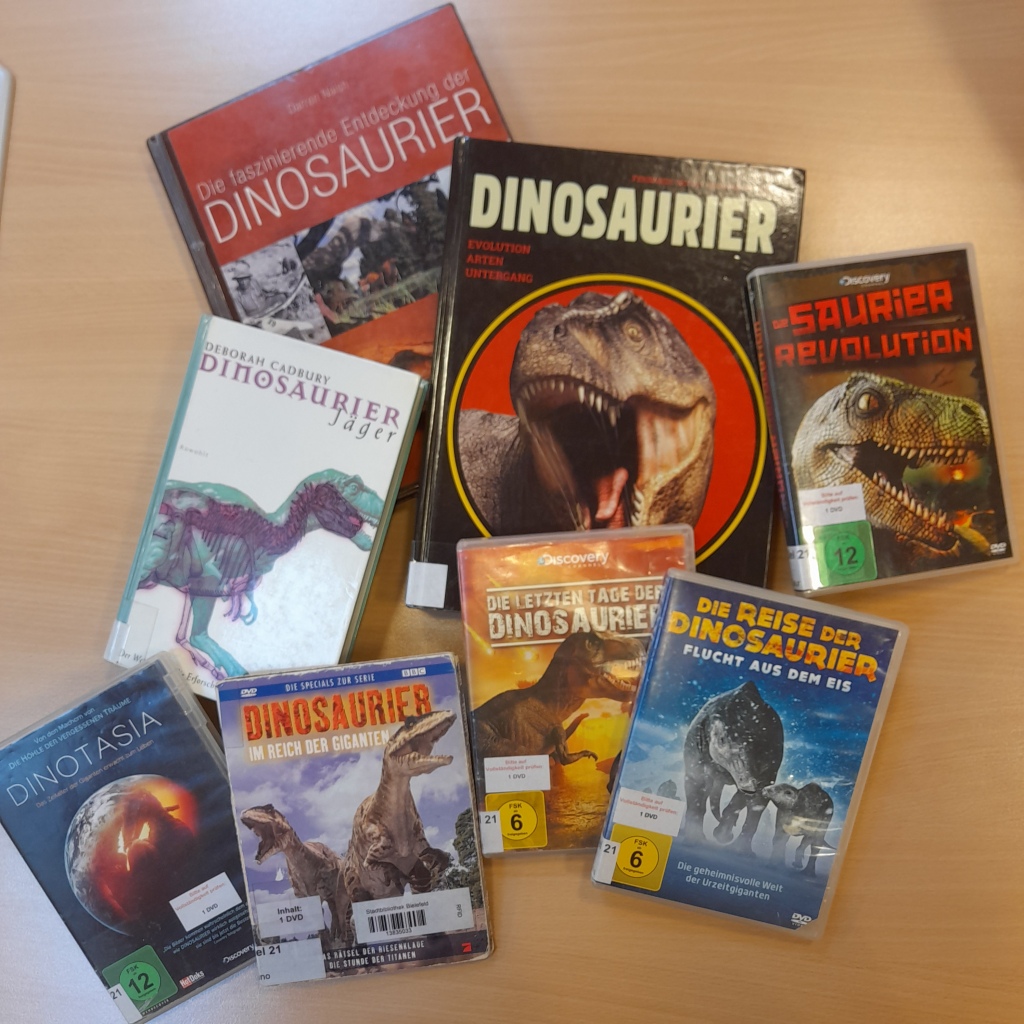 Mehrere Bücher und DVDs über Dinosaurier liegen auf einem Tisch