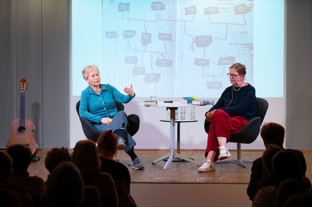 Foto: Ulrike Draesner im Gespräch mit Moderatorin Antje Doßmann auf der Bühne; als Bühnen-Hintergrund ein grob gemalter Stammbaum 