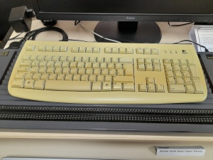 Foto von einer alten Computertastatur, die auf einer flachen, schwarzen Apparatur steht.